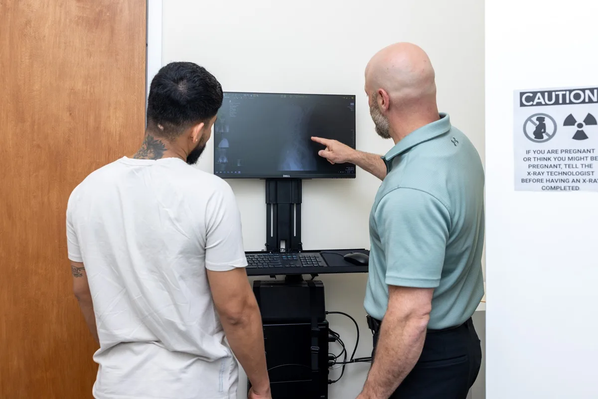 Chiropractor reviewing x-ray images on a monitor with a patient